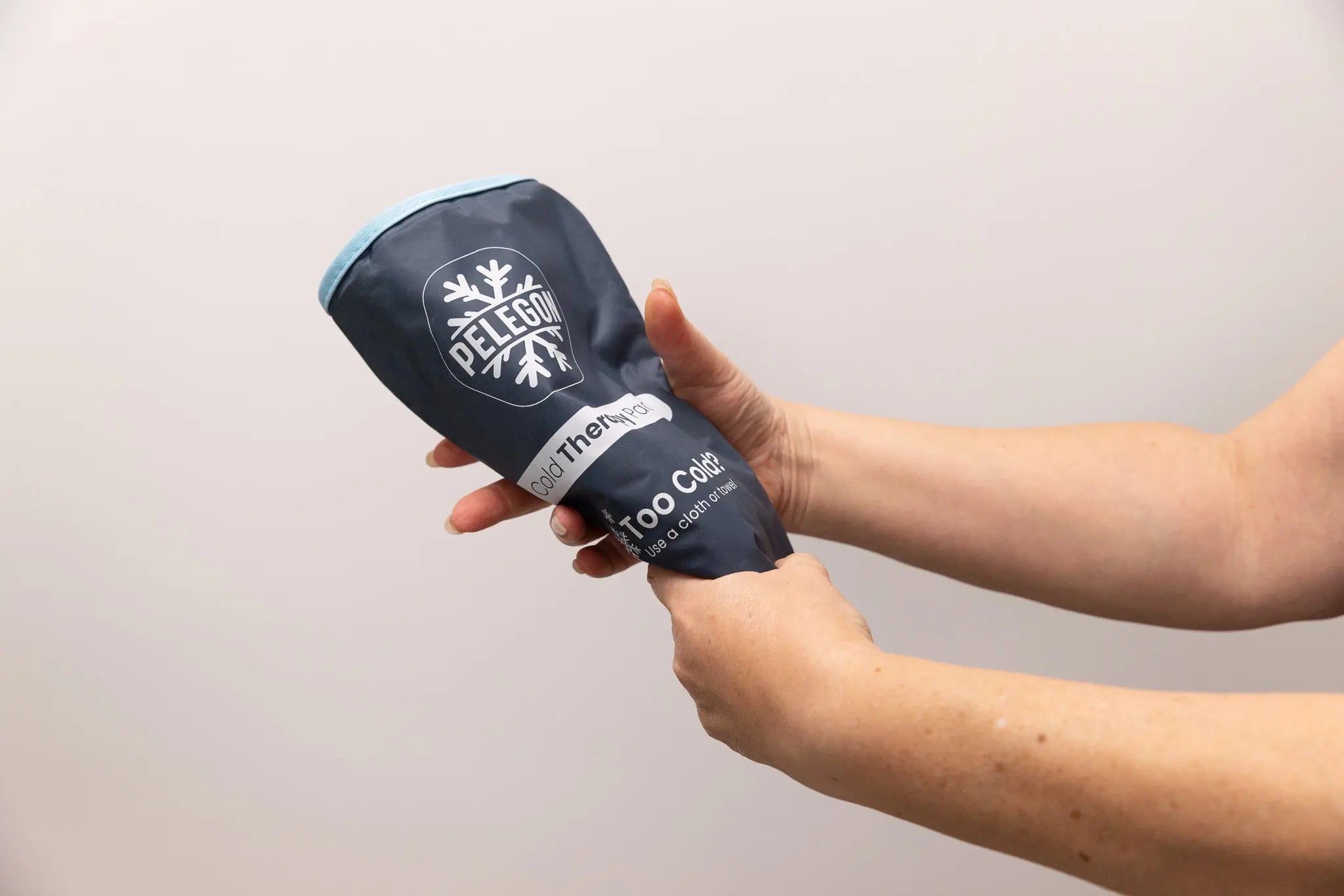 Hands flexing a Pelegon reusable ice pack for targeted cold therapy and pain relief.