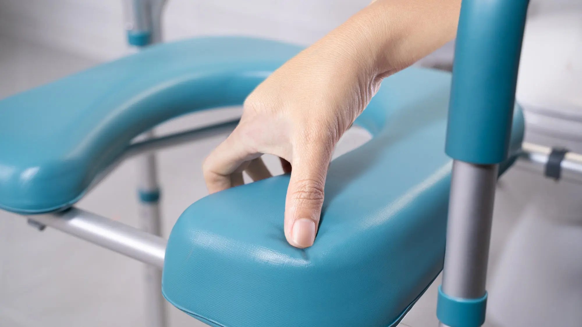 Pelegon's raised toilet seat with handles, showing the soft cushioned surface designed to improve comfort and support for seniors and individuals with limited mobility.