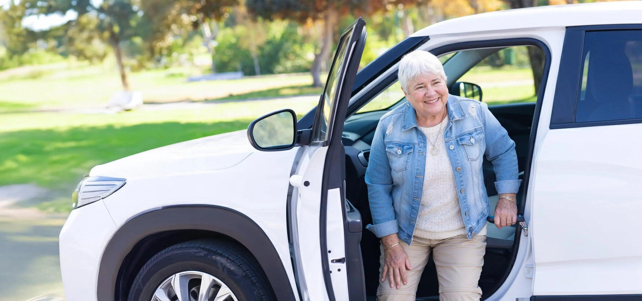 Elderly woman using a car door handle for elderly support while safely exiting a vehicle.