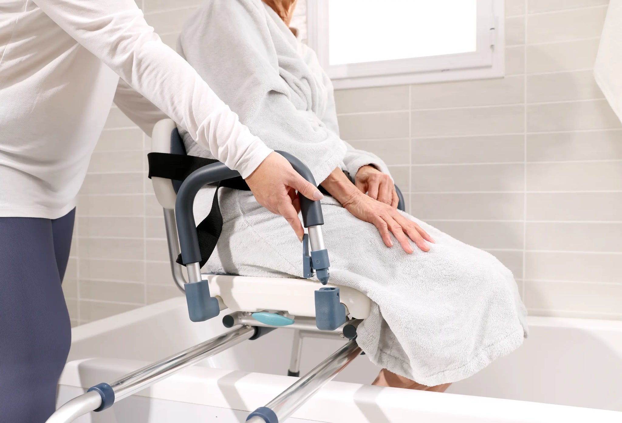 enior using a tub transfer bench for safe bathtub transfers with caregiver assistance.