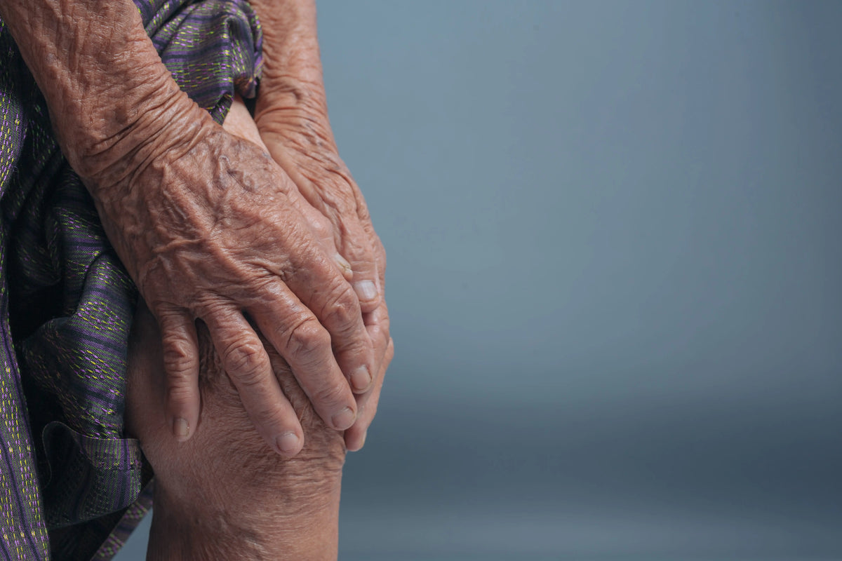 Senior holding a painful knee affected by arthritis and joint stiffness.