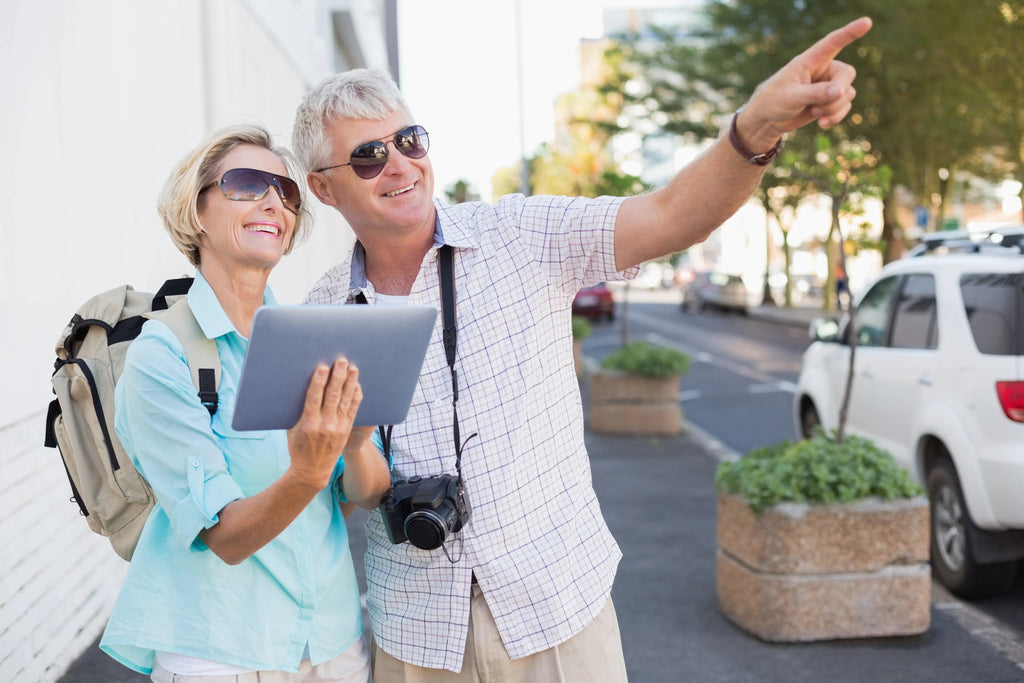 Senior couple traveling with a tablet, smiling and exploring the city together - senior travel tips in action.