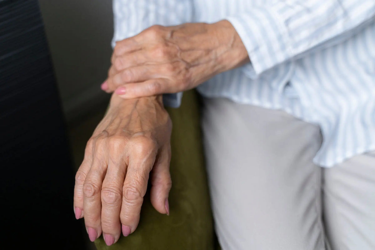 Older woman holding her wrist while experiencing arthritis pain and stiffness in her hands and joints.