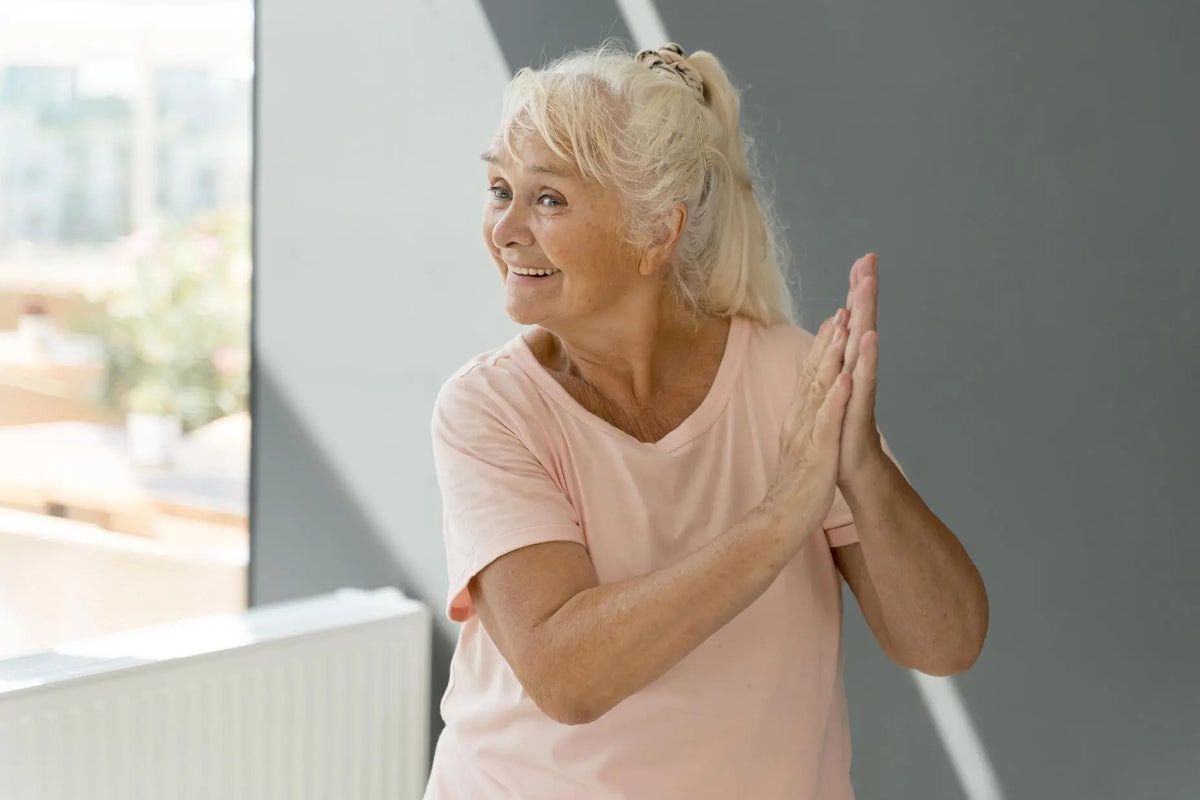 Senior woman smiling and clapping her hands during a dance exercise class.